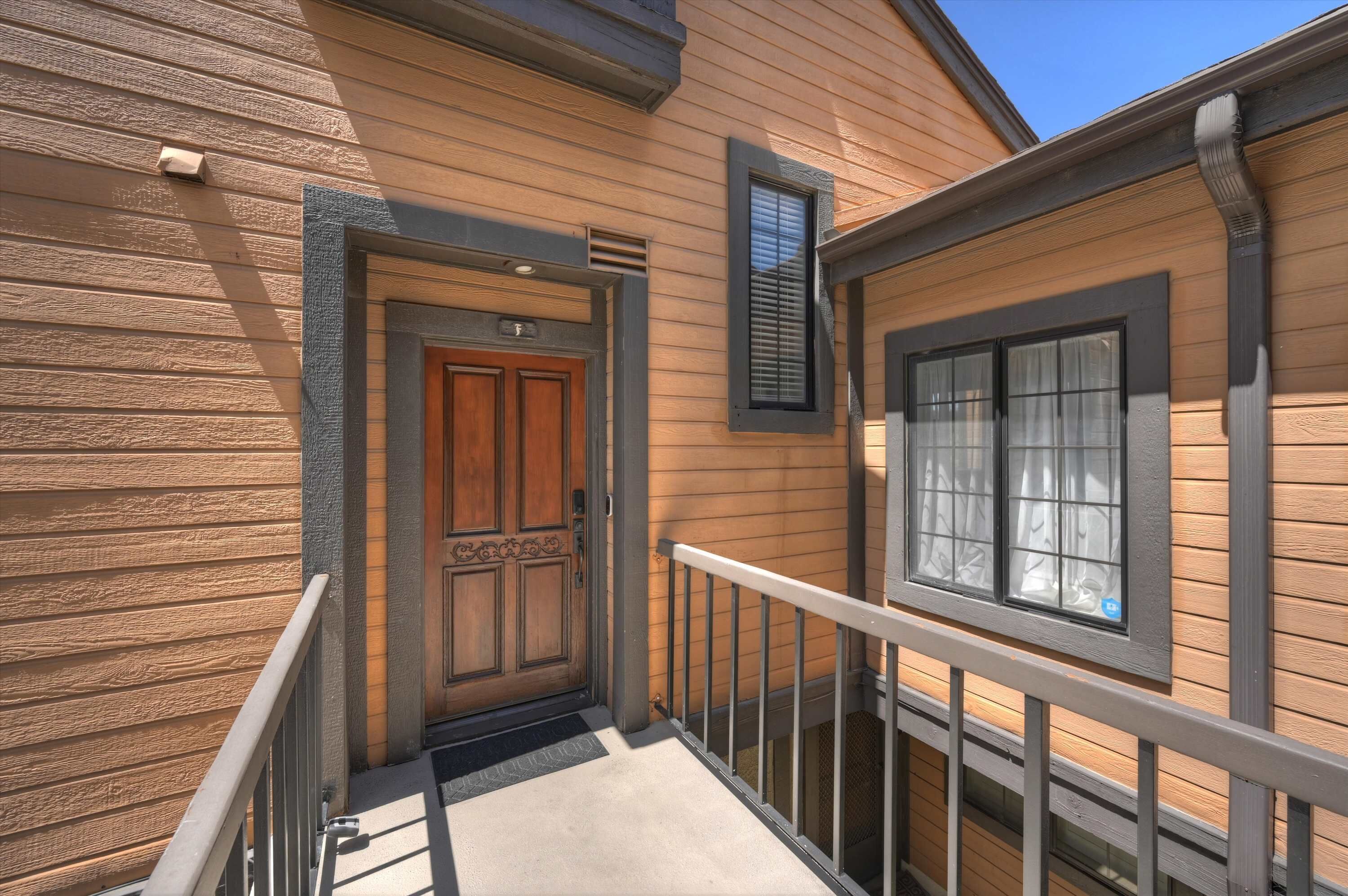 A wooden exterior with a double door, a window with blinds, and a metal railing.