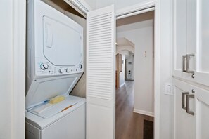 Un lavadero con lavadora y secadora de carga frontal, una puerta que da a un pasillo y un interruptor de luz en la pared.