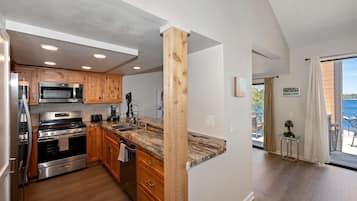 A modern kitchen with wooden cabinets, stainless steel appliances, and a large window overlooking a balcony.
