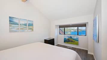 Un dormitorio con cama, ventana con vistas y tres cuadros en la pared.