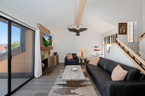 Un salon moderne avec une cheminée, un canapé, une table basse et un escalier.