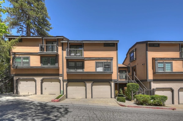 A multi-story residential building with a central staircase, balconies, and garage doors.