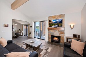 Una sala de estar moderna con chimenea, televisor y comedor con vistas.