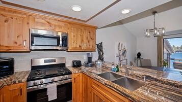 Una cocina moderna con gabinetes de madera, electrodomésticos de acero inoxidable, encimeras de granito y un ventanal grande.