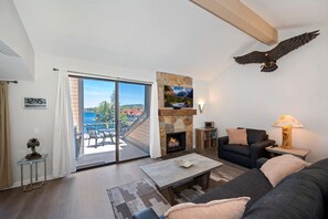Un salon moderne avec une cheminée, un canapé, une table basse et une vue sur l’extérieur.