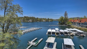 A lakeside dock area with boats, a clear sky, and buildings in the background.