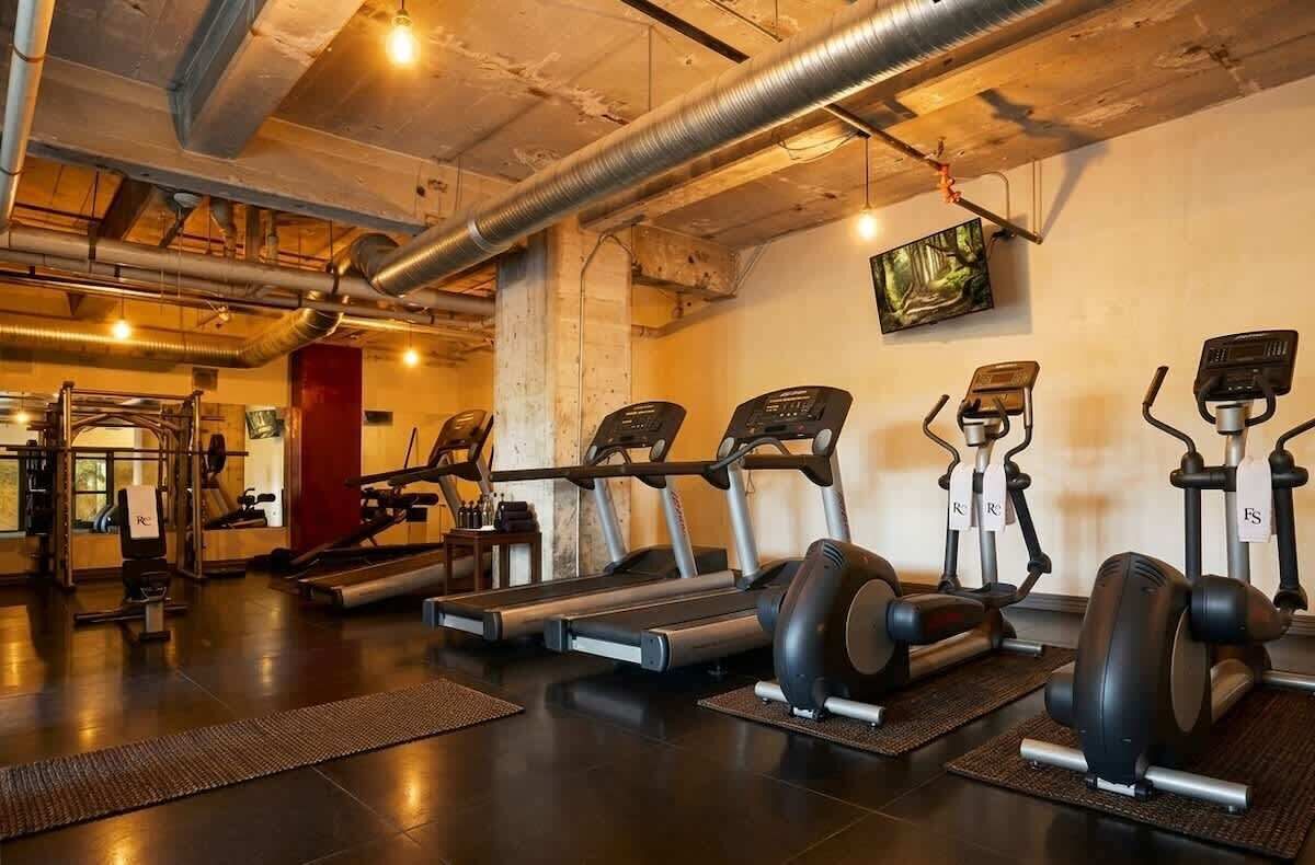 Una palestra con tapis roulant, macchinari ellittici e postazioni per pesi.