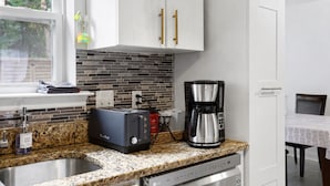 A kitchen with a toaster, coffee maker, and a dish rack.
