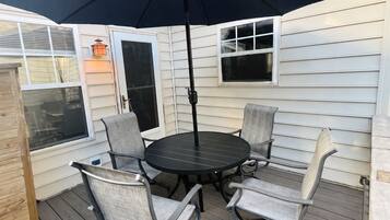 An outdoor patio with a round table and four chairs, an umbrella, and a lantern.
