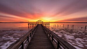 A wooden pier leading to a structure at sunset.