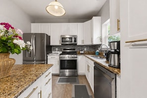 A modern kitchen with white cabinetry, stainless steel appliances, a granite countertop, and a hanging light fixture. - Luxury 3BR Near Quantic, Fort Belvoir,Town Cen,Potomac Mills,Beaches, Parks & DC (Woodbridge)