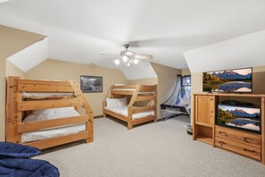 A room with bunk beds, a ceiling fan, a TV, and a small cabinet. - Lakeside Haven: Boat Dock, Ramp, Games, & MORE! (Sevierville)