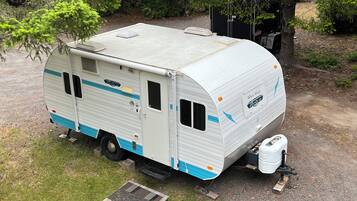 Un camping-car blanc à rayures bleues est garé sur une surface de gravier.