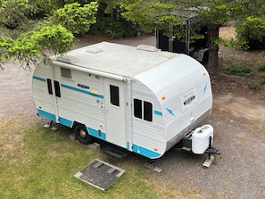 Un camping-car blanc à rayures bleues est garé sur une surface de gravier.