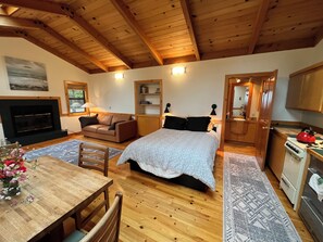 Ein gemütliches Zimmer mit einem Bett, einem Sofa, einem Esstisch, einem Kamin und einer Küchenzeile.