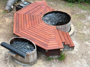 A hot tub with a wooden deck and two wooden tubs.