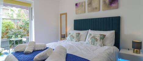 A bedroom with a bed, a nightstand, a lamp, a mirror, and artwork on the wall.