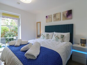 Quarto com cama, mesa de cabeceira, luminária, espelho e obras de arte na parede.