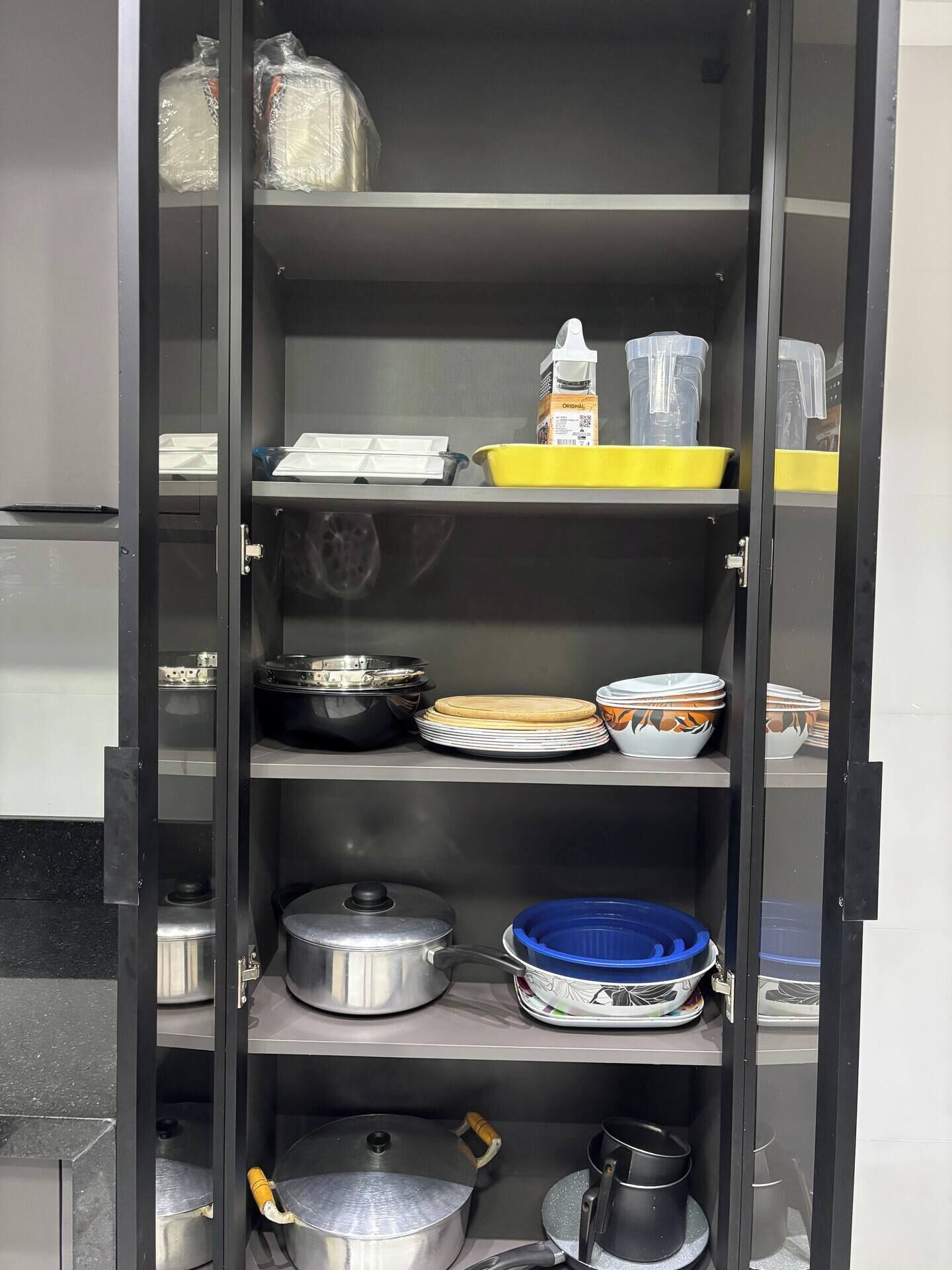 A kitchen cabinet with shelves containing various kitchenware items.