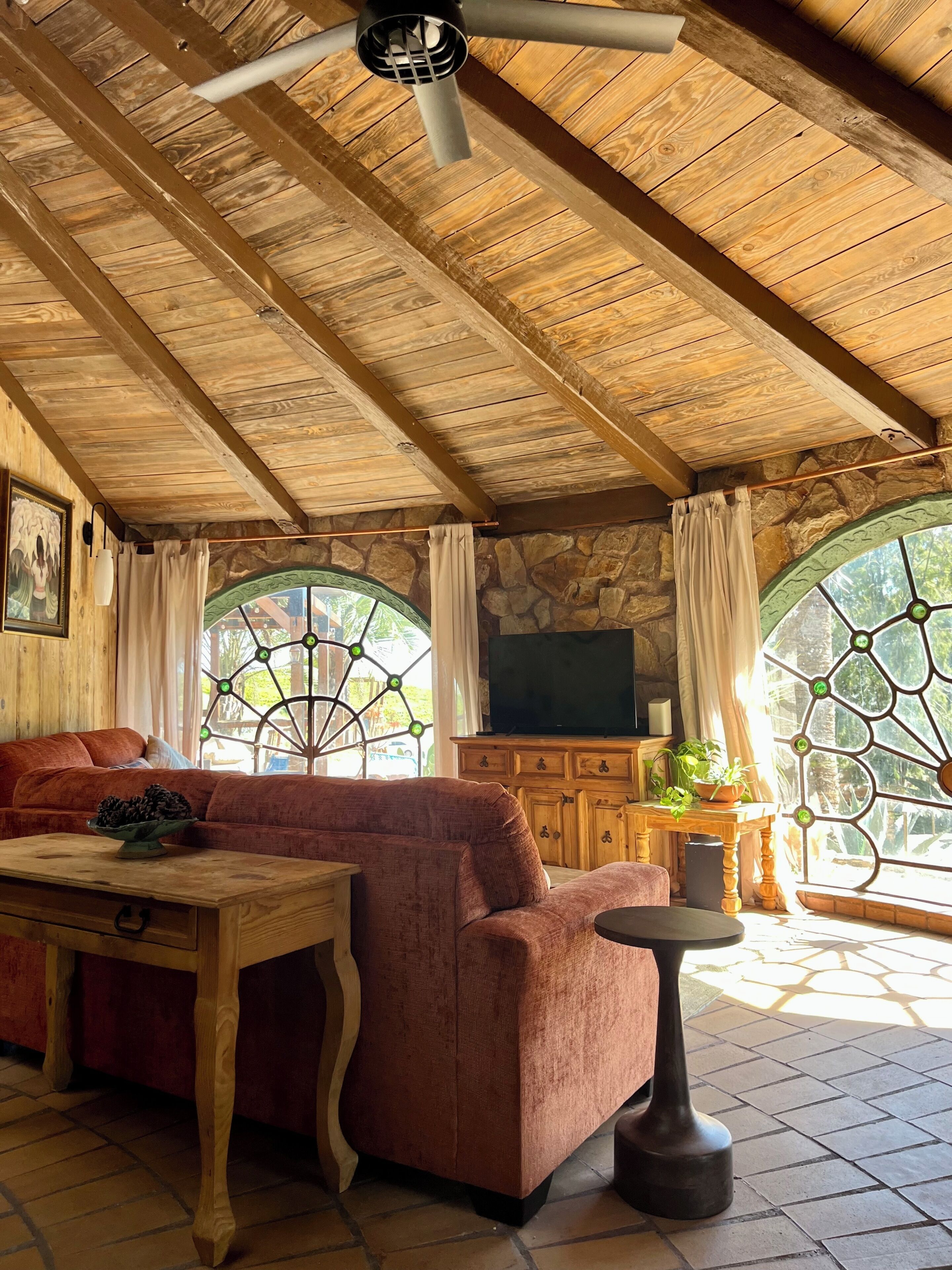 Une pièce chaleureuse avec un plafond en bois, un canapé, une table et un mur en pierre.