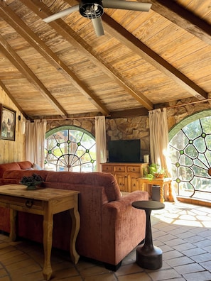 Ein gemütliches Zimmer mit Holzbalkendecke, einer Couch, einem Tisch und einer Steinwand.