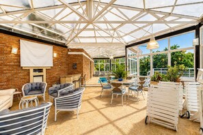 A covered patio area with brick walls, a pool, and outdoor furniture. - Casa de Campo com Lago Piscinas Jacuzzi e Sauna (Atibaia)