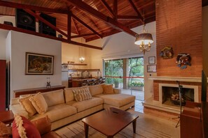 A spacious living room with a large sofa, a fireplace, and a kitchen in the background. - Casa de Campo com Lago Piscinas Jacuzzi e Sauna (Atibaia)