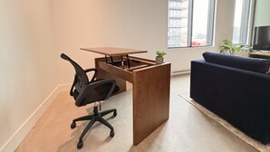 Ein moderner Arbeitsraum mit einem Holztisch, einem schwarzen Bürostuhl und einem dunkelblauen Sofa.