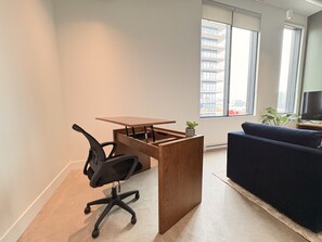 A modern office space with a wooden desk, black office chair, and a dark blue sofa. - 1 BR Industrial-Chic Penthouse Loft | City Views (Halifax)