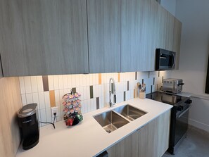 Uma cozinha moderna com micro-ondas embutido, cafeteira e pia de aço inoxidável.