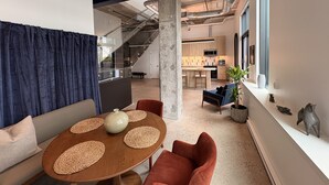 Ein modernes Interieur mit einem runden Holztisch, zwei Stühlen, einer Couch, einer Treppe und einer Küchenzeile.