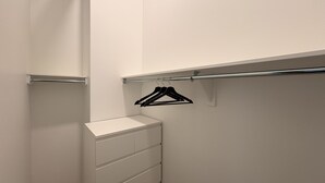 Ein weißer Schrank mit Kleiderstange und Schubladen.