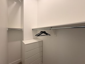 A white closet with a hanging rod and a set of drawers. - 1 BR Industrial-Chic Penthouse Loft | City Views (Halifax)