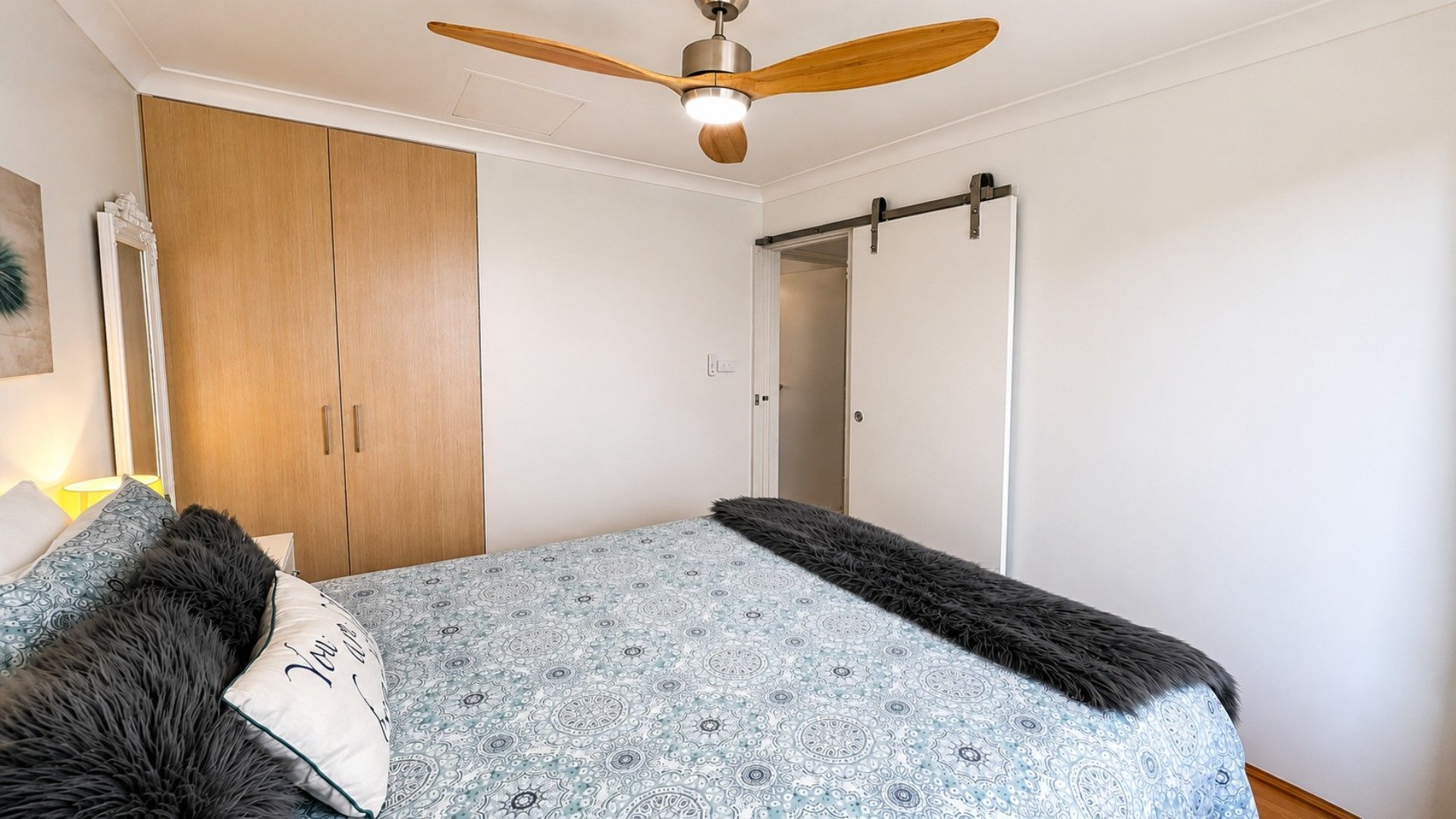 Una camera da letto con un letto, un armadio, una ventola a soffitto e una porta.