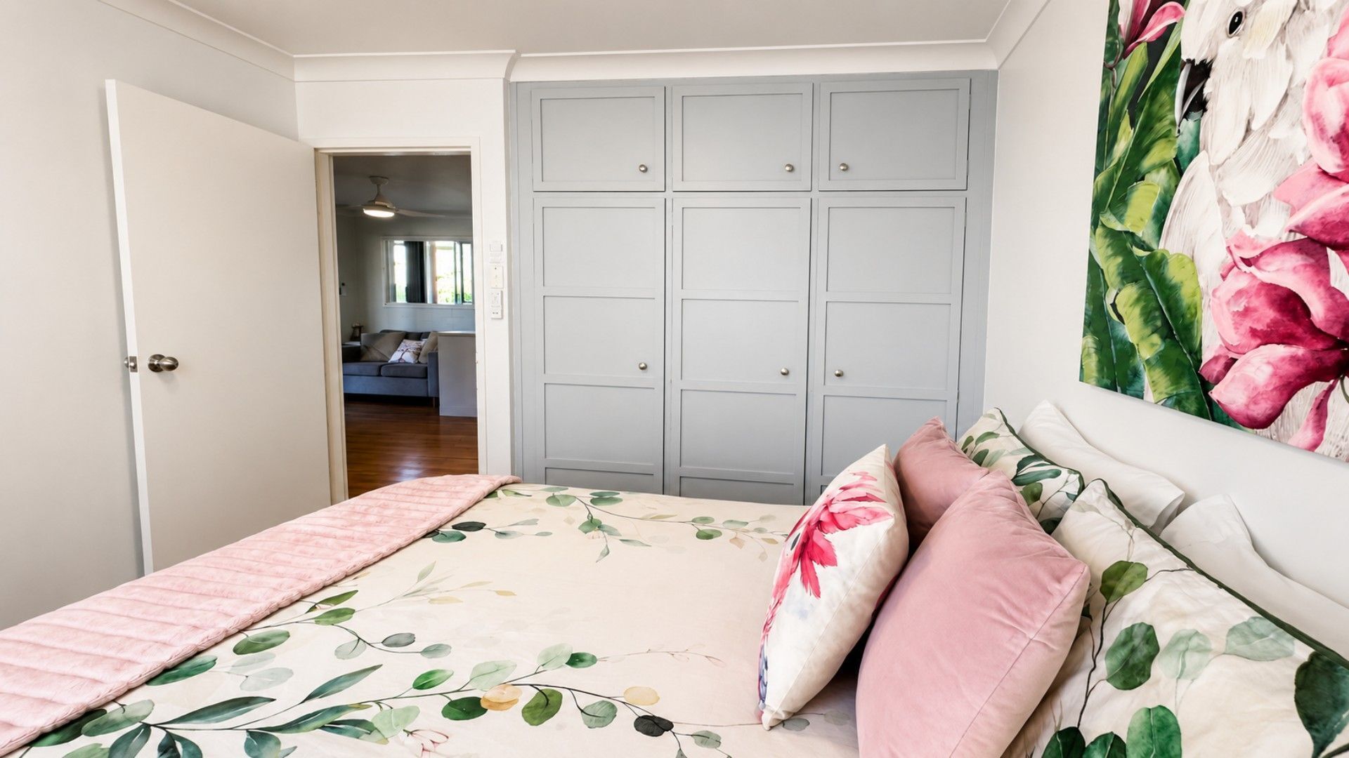 A bedroom with a bed, a wardrobe, and a painting on the wall.