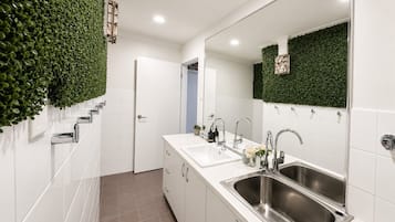 A modern bathroom with a white vanity, two sinks, a large mirror, and green wall accents.