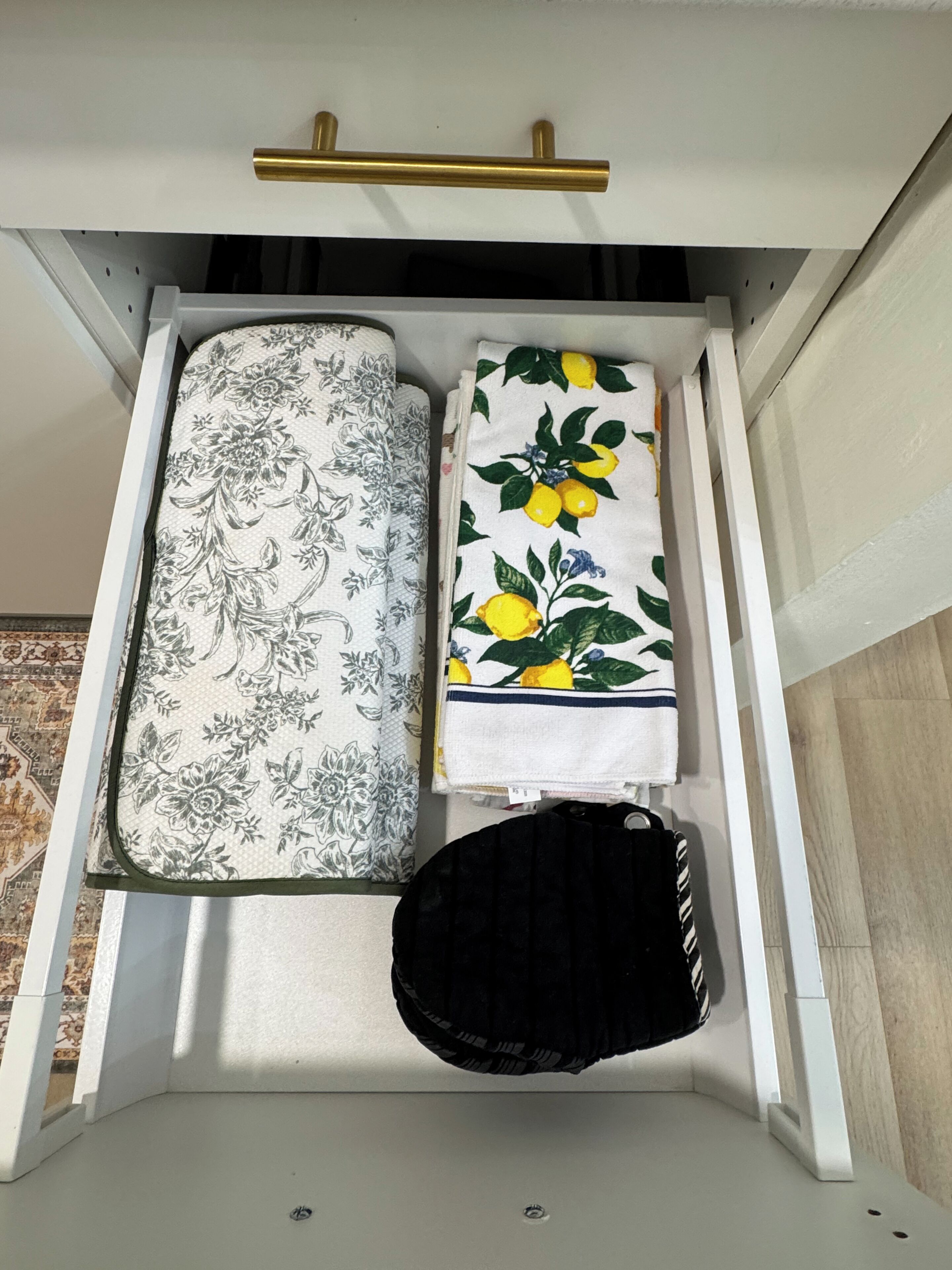 Un tiroir recouvert d’un tissu à motifs floraux, d’un tissu à motifs de feuilles de citron et un sac noir.