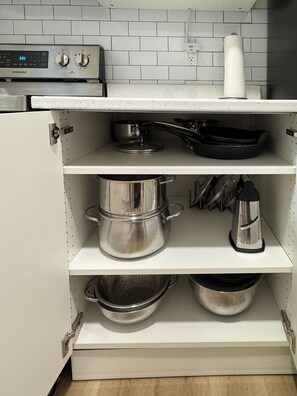 Une cuisine équipée d’appareils électroménagers en acier inoxydable, notamment une cuisinière et un four à micro-ondes, et dont le mur derrière l’évier est recouvert de carreaux blancs.