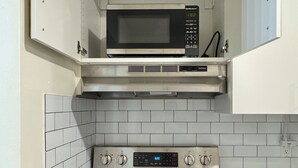 A compact kitchen with a built-in microwave above a stainless steel stove and oven. - Modern 2BR | Near Victoria Hospital (London)
