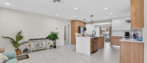 Una cocina moderna con una isla central, armarios de madera y un rincón de comedor con un sofá azul claro.