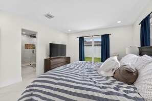 A bedroom with a bed, a TV, a dresser, and a sliding glass door to a balcony. - Cabana Retreat Private Dock (Pompano Beach)