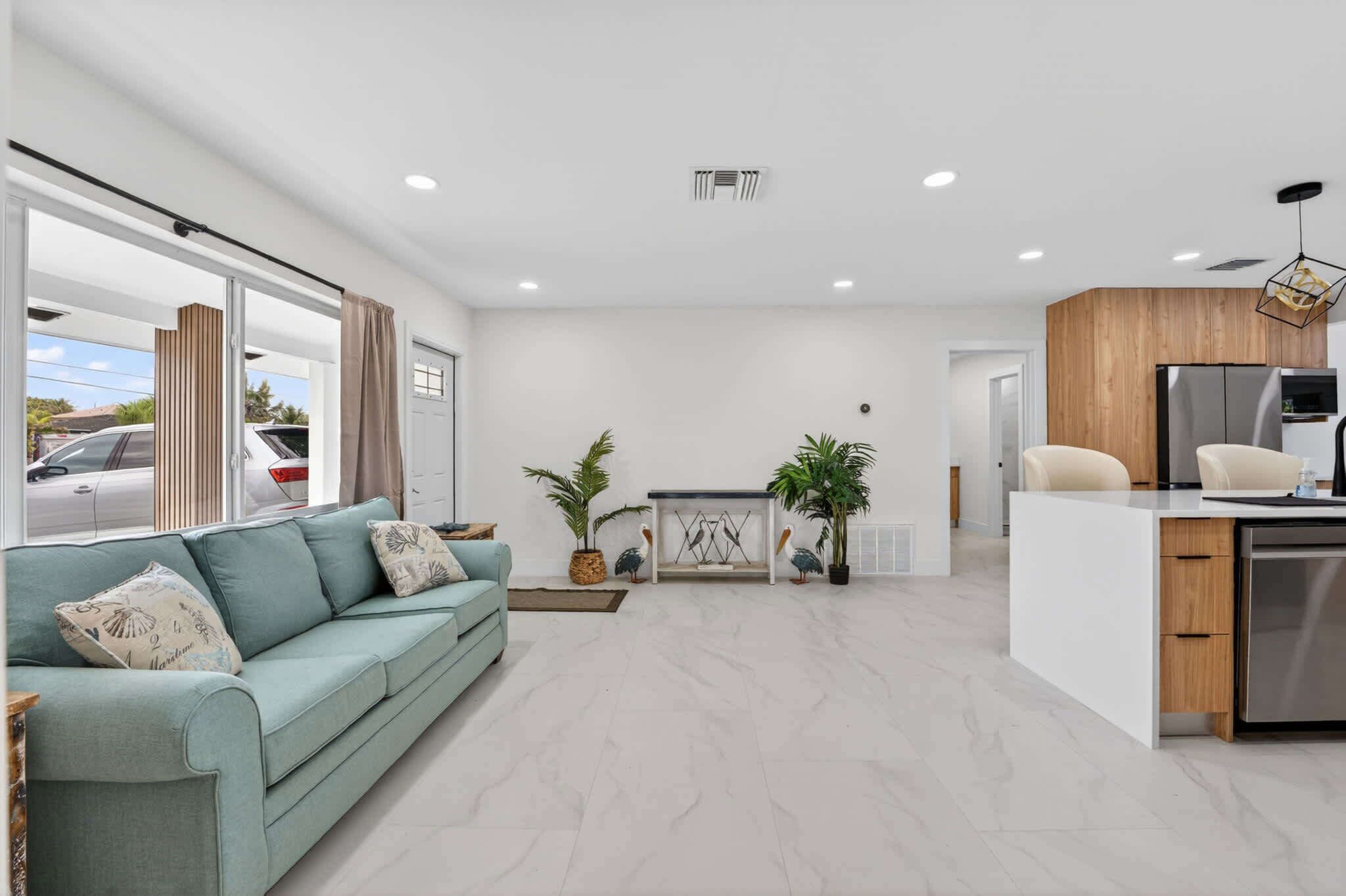 Una sala de estar moderna con un sofá, una mesa de centro y una zona de cocina con un refrigerador y un lavabo.