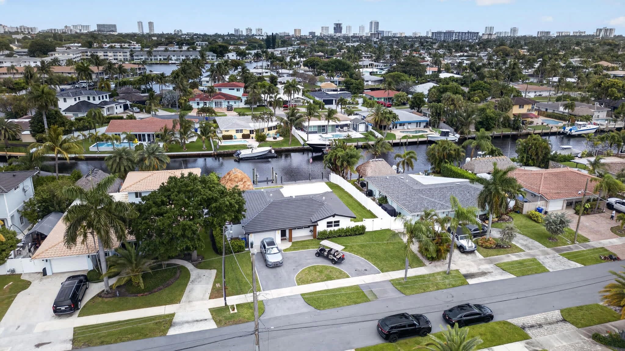 A residential area with houses, palm trees, and a marina with boats.