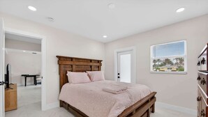 A bedroom with a wooden bed frame, a pink bedspread, and a window with blinds. - Cabana Retreat Private Dock (Pompano Beach)