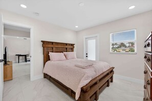 A bedroom with a wooden bed frame, a pink bedspread, and a window with blinds. - Cabana Retreat Private Dock (Pompano Beach)
