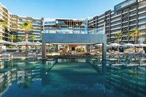 Ett modernt hotell med en central pool, flera balkonger och utomhusområden med sittplatser.
