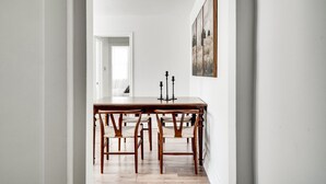 Un pasillo que conduce a un comedor con una mesa y sillas de madera, un cuadro en la pared y una puerta al final.