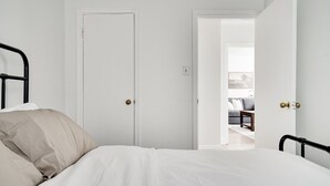 Un dormitorio con una cama, una puerta y un vano abierto que da a otra habitación.