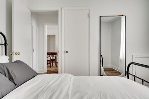 A bedroom with a bed, a mirror, and a door leading to another room. - Bright 2BR – Walk to Downtown Kingston & Lake! (Kingston)