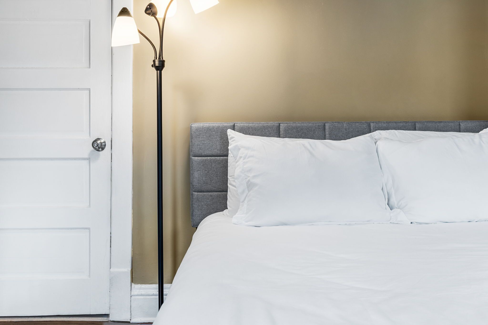 A hotel room with a bed, a nightstand, a lamp, and a door.